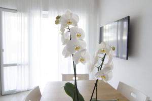 two white flowers in a vase on a table at Appartamenti Federica in Milano Marittima