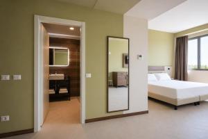 a bedroom with a bed and a mirror and a sink at LVG Hotel Collection - Belfiore in Mantova