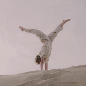 a person doing a handstand in the sand at Dania Surf House in Mirleft
