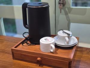 a coffee maker and two cups on a wooden table at Dalem Kamulyan Kraton in Timuran