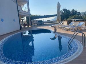 a swimming pool with some chairs and an umbrella at Vila Pepic in Dobra Voda