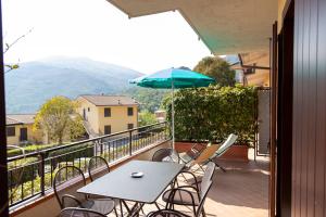 a table and chairs on a balcony with an umbrella at Residence Primera Rompala, GTSGroup in Tignale