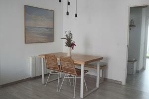 ein Esstisch mit zwei Stühlen und einer Vase mit Blumen in der Unterkunft Darahome in Cunit + 22 Fotos