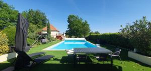 a backyard with a table and chairs and a swimming pool at La Chesnaie in Bonnes