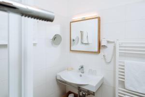 ein weißes Badezimmer mit Waschbecken und Spiegel in der Unterkunft Boutique Hotel Kögele Innsbruck Axamer Lizum in Innsbruck