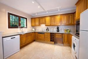 a kitchen with wooden cabinets and a white dishwasher at Casa El Trebol in L'Escala