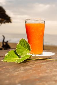 a glass of beer sitting on a plate with a green leaf at Tsunami beach hotel arugambay in Pottuvil