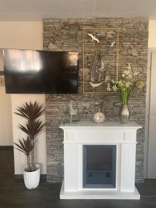 a fireplace with a television on a stone wall at Homoki Wellness Üdülőház in Balatonakarattya