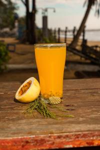 a glass of orange juice next to a piece of fruit at Tsunami beach hotel arugambay in Pottuvil +31 photos
