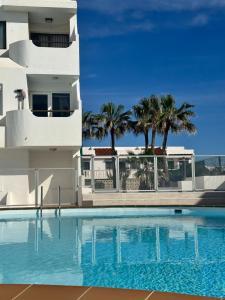 a swimming pool in front of a building with palm trees at Casa Tropical in Costa de Antigua
