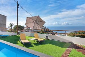 a patio with two chairs and a table and an umbrella at Casa Carreira in Ponta do Sol