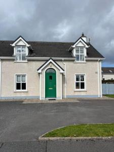 a large house with a green door on a street at Rougey Lodge Hostel in Bundoran