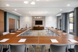 a conference room with tables and chairs and a screen at EVEN Hotel Alpharetta - Avalon Area by IHG in Alpharetta