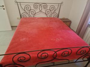 a metal bed with a red blanket on it at Guest House Perla in Sveti Juraj