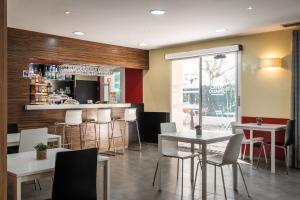 a restaurant with tables and chairs and a bar at Hotel Canal Olímpic in Castelldefels