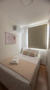 a white bedroom with a large bed with a window at Flat 707 Moderno e Espaçoso, próximo ao Praia Clube in Uberlândia +19 photos