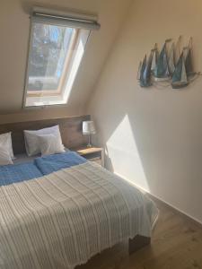 a bedroom with a bed with a window and a boat on the wall at Homoki Wellness Üdülőház in Balatonakarattya