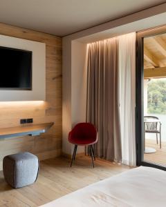 a bedroom with a red chair and a television at Agriturismo Vedova in Valdobbiadene