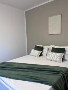 a bedroom with a large bed with green and white pillows at Vila Happy House in Costinesti