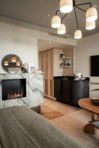 a living room with a fireplace and a kitchen at CORI Hornbæk Hotel in Hornbæk