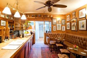 a restaurant with a bar with booths and a ceiling fan at The Acorn Inn in Evershot