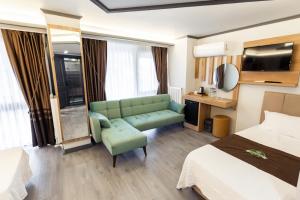 ein Hotelzimmer mit einer grünen Couch und einem Bett in der Unterkunft Hotel Milano in Rize