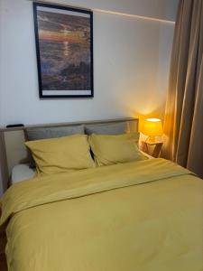 a bedroom with a yellow bed with a picture on the wall at Sunny Apartment in Constanţa