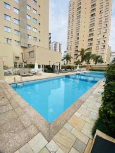 a large blue swimming pool with two tall buildings at Flat Vila Olimpia Hotel Experience in São Paulo