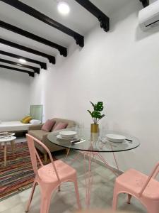 a dining room with a glass table and pink chairs at Galteo Alameda in Ronda