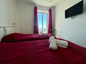 a bedroom with two beds with red sheets and a window at Il Colle in Sanremo