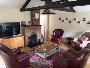 a living room with leather furniture and a fireplace at Claire Cottage in Selby