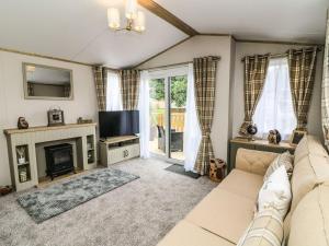 a living room with a couch and a television at Hedgehog Lodge in Carnforth