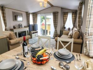 a table with a bowl of fruit and a bottle of wine at Hedgehog Lodge in Carnforth