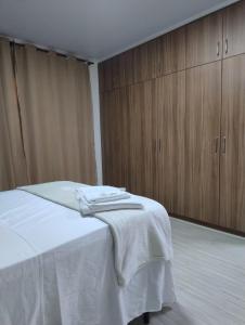 a bedroom with a bed with white sheets and wooden cabinets at Hospedaria AlpenGlück in Treze Tílias