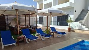 a patio with chairs and umbrellas and a pool at Malak house swimming pool &Garden in Luxor