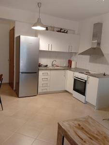a kitchen with white cabinets and a refrigerator at Penelope apartment in Neoi Epivates +8 photos