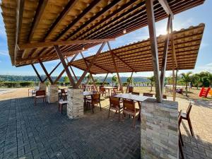 a patio with tables and chairs under a wooden roof at yes banana in Bananeiras