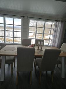 ein Esszimmer mit Tisch, Stühlen und Fenstern in der Unterkunft T - Stua in Moen i Målselv