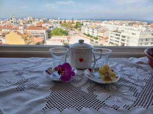 a table with two glasses and a tea pot and flowers at Minha Alegre Casinha in Sines