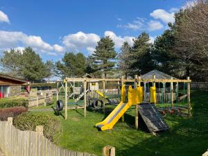 a playground with a yellow slide in the grass at 26 Ocean View in Llwyngwril