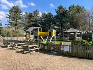 a playground with picnic tables and a play structure at 26 Ocean View in Llwyngwril