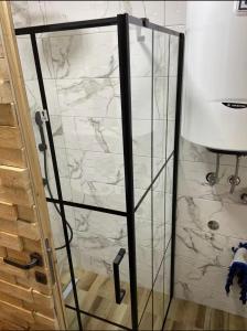 a glass shower door with a white marble wall at Black Pine Chalet in Meždo