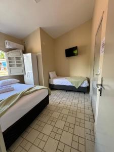 a room with two beds and a tv on the wall at Pousada Pedra que Canta in Itamaracá