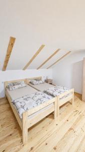 two beds in a room with wooden floors at River Valley Guest House in Foča