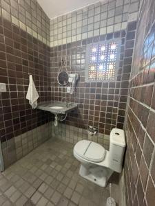 a tiled bathroom with a toilet and a sink at Pousada Pedra que Canta in Itamaracá +54 photos