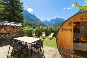 a table and chairs on a patio with mountains in the background at JASNA NATUR Resort by the lake in Kranjska Gora