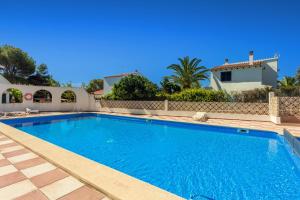 a large blue swimming pool in front of a house at Bon repós B5 in Cala en Bosc