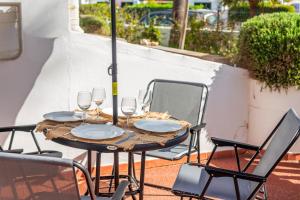 a table with wine glasses and chairs on a patio at Bon repós B5 in Cala en Bosc