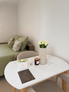 a white coffee table with a vase of flowers on it at NAIA apartment in Koper