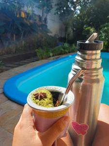 a person holding a bowl of food next to a bottle at Villa Serena, próx do Aeroporto in Porto Alegre